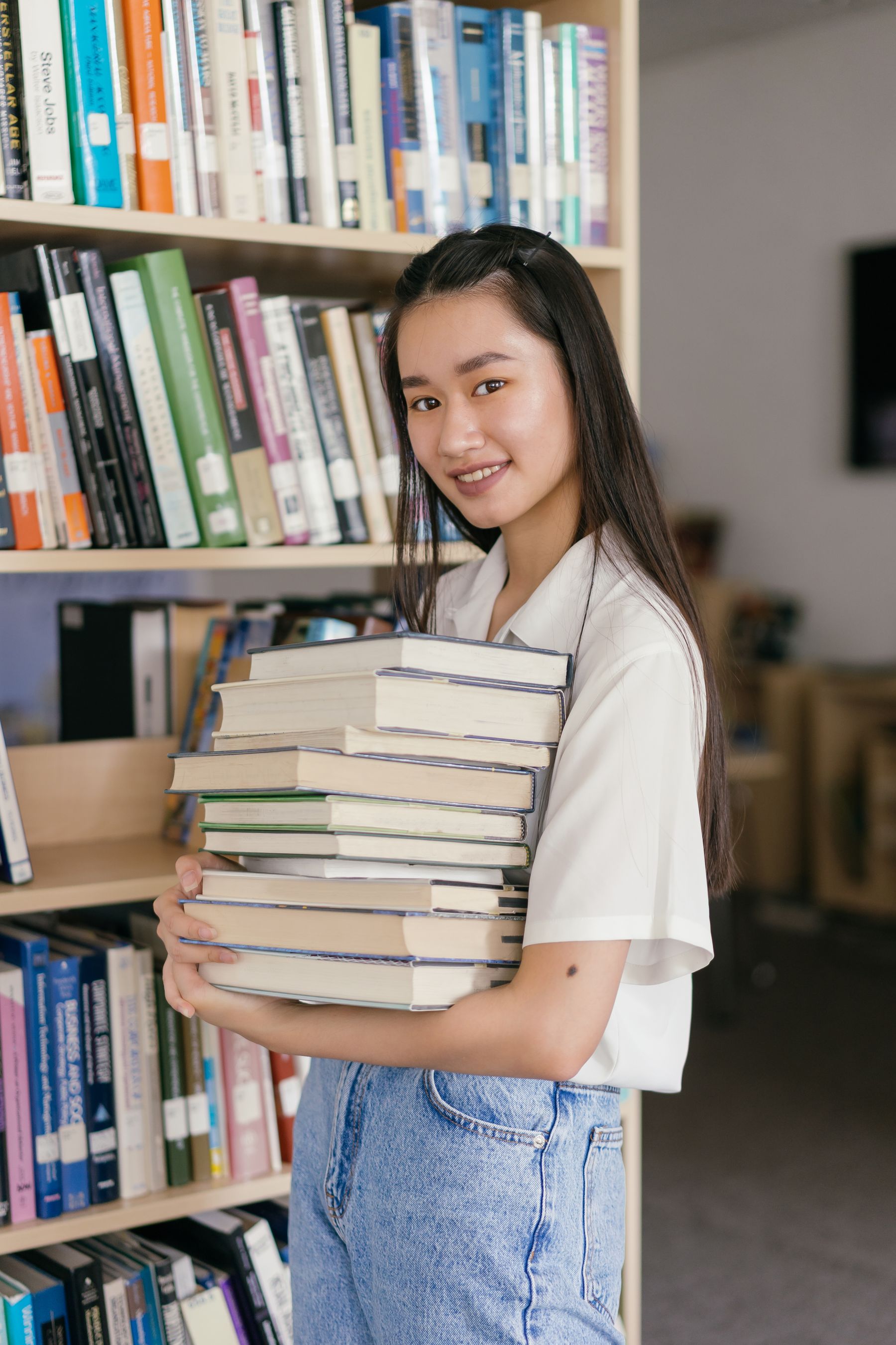A student smiling and holding a stack of books