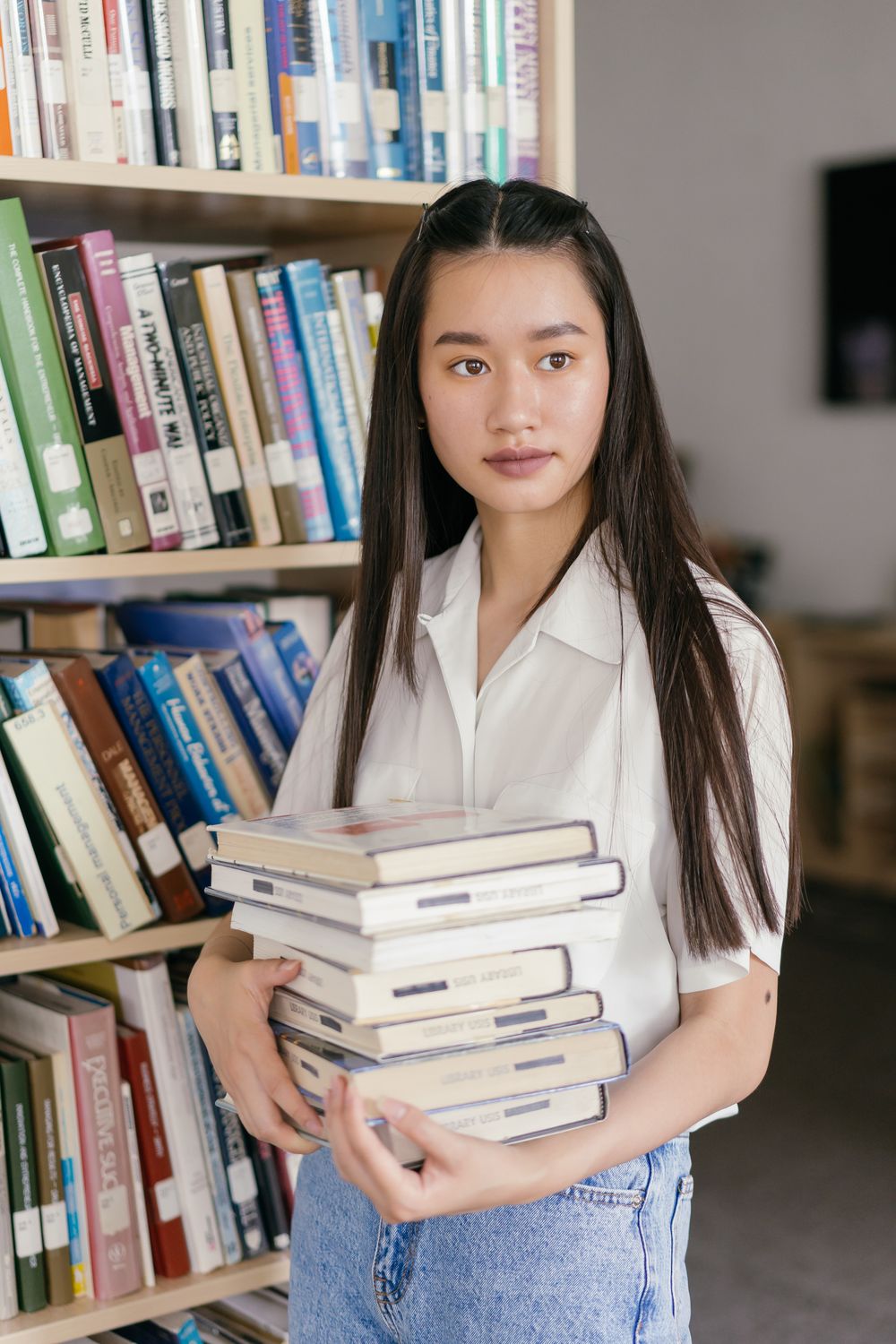 A student holding books in a library